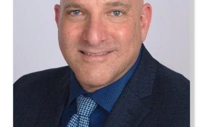 Mitch Kahn, a smiling bald man in a blue