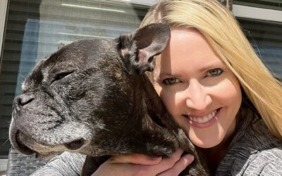 Crystal Rasor smiling, hugging her brindle French