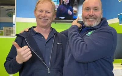 Two smiling men, one giving a