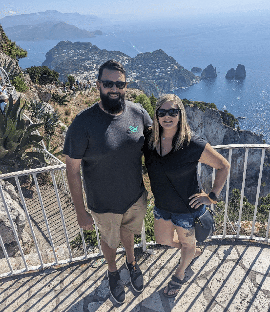 Smiling couple at a scenic coastal viewpoint overlooking a